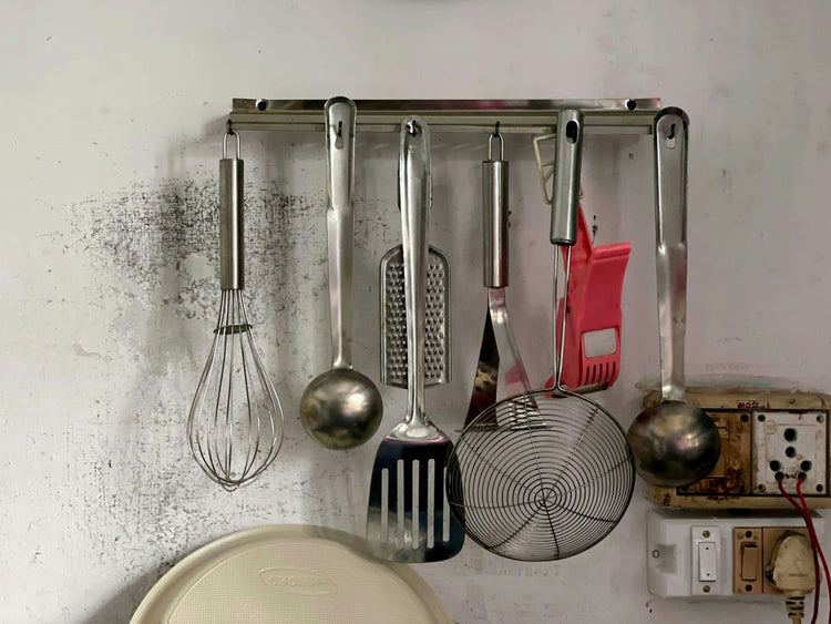 Wall-mounted kitchen tools, including a whisk, ladle, spatula, and grater, ideal for efficient cooking and organization